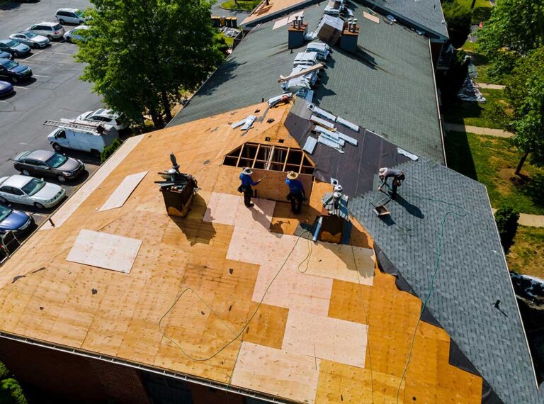 A homeowner examining roof shingles for damage on a residential rooftop after a storm.