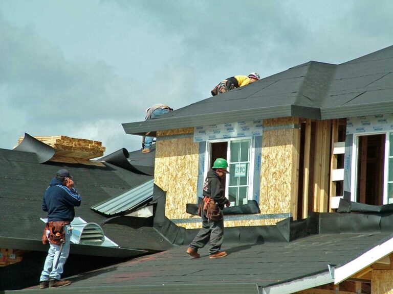 A local home with both flat and sloped roofs visible, with seasonal trees in the background.